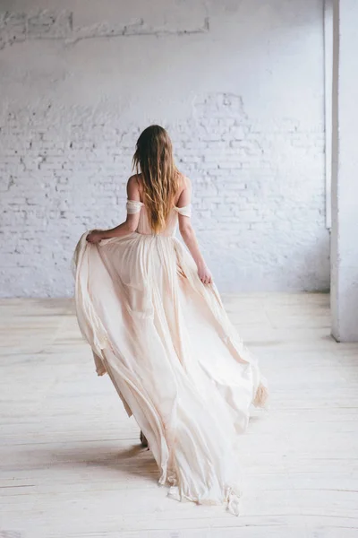Fashion model in een mooie beige vloeiende jurk. — Stockfoto
