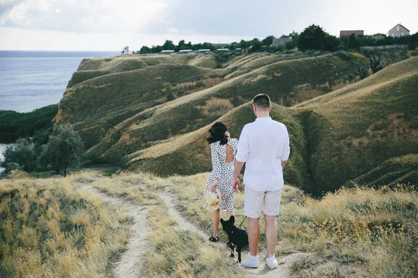 Buiten portret van jonge zwangere paar in veld en uitzicht op zee — Stockfoto