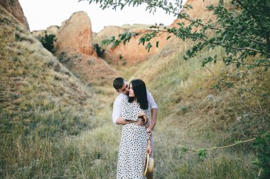 Polka nokta elbiseli hamile kadın buğday tarlasında ayakta ve saçlarını ve onu öpüşme adam dokunmadan