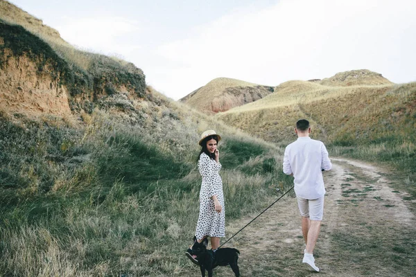 Outdoor portrait of walking young pregnant couple in field — Stock Photo, Image