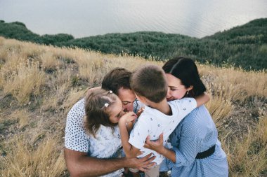 Mutlu ebeveynler ve çocuklar bir buğday tarlasında açık havada eğleniyor.