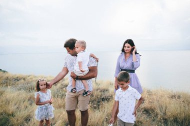 Mutlu ebeveynler ve çocuklar bir buğday tarlası ve nehir görünümünde açık havada konuşan.