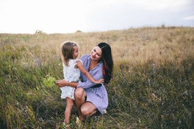 Anne ve kızı ilkbaharda buğday tarlasında dinleniyor.