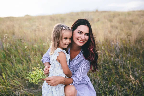 Mother and daughter are relaxing and smiling in wheat field at spring time. — Stock Photo, Image