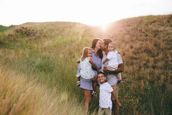 Glücklicher Vater und Kinder, die sich umarmen und Spaß im Freien in einem Weizenfeld haben. Sonnenuntergang — Stockfoto