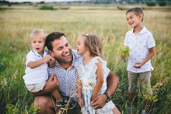 Gelukkige vader en kinderen plezier buitenshuis in een tarwe veld. — Stockfoto