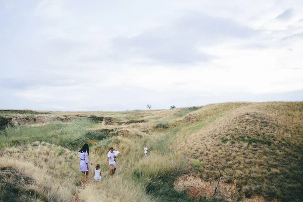 Happy parents and children are walking outdoors in a wheat field view. — Stock Photo, Image