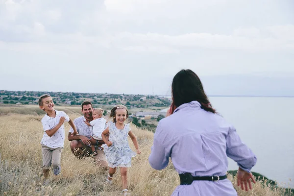 Happy parents and children having fun outdoors in a wheat field and river view. — Stock Photo, Image