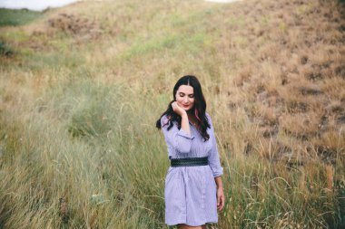 Bir buğday tarlası backgrond açık havada duran mavi elbiseli gülümseyen kadın