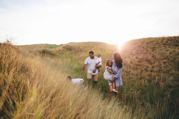 Gelukkige ouders en kinderen knuffelen en plezier maken buitenshuis in een tarwe veld. Zonsondergang — Stockfoto