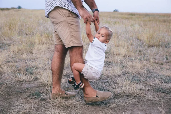 Sorrindo criança abraçando seu pai e segurando sua perna — Fotografia de Stock