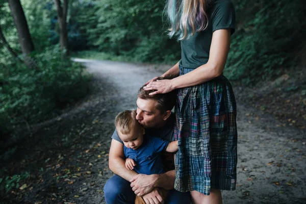 Ευτυχισμένος νεαρός οικογενειακός πατέρας, μητέρα και μικρός γιός Αγκαλιάζοντας και αγγίζοντας εξωτερικούς χώρους, παίζοντας μαζί στο καλοκαιρινό πάρκο Φωτογραφία Αρχείου