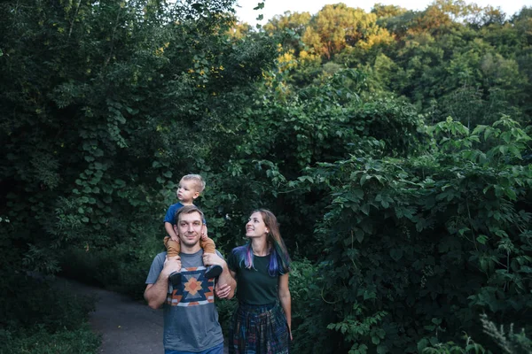 Счастливая веселая молодая семья отец, мать и маленький сын веселятся на свежем воздухе, играя вместе в летнем парке Стоковая Картинка
