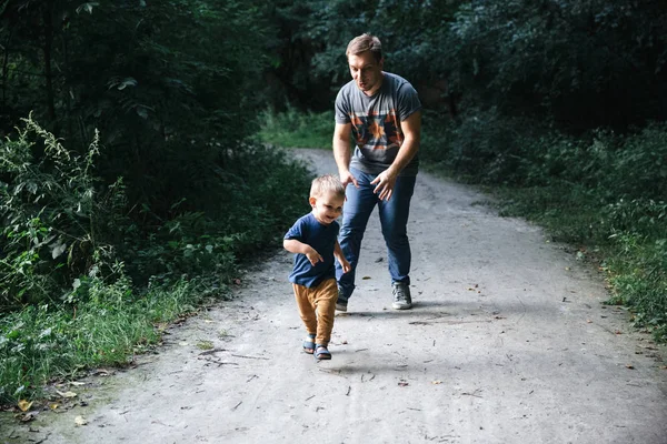 Счастливый веселый молодой отец и маленький сын веселятся на свежем воздухе, играя вместе в летнем парке Стоковое Изображение