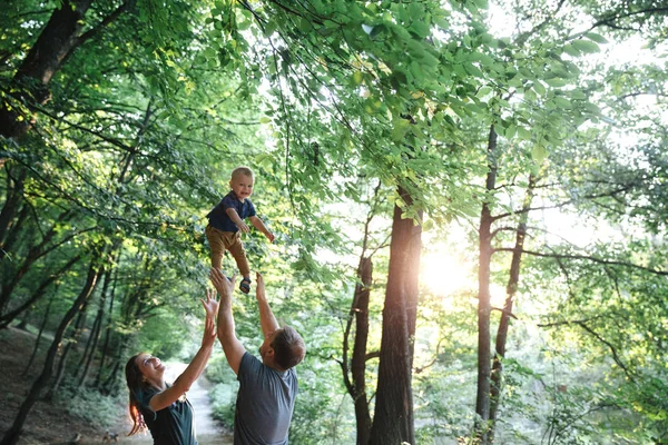 Щасливий радісний молодий батько сім'ї, мати і маленький син розважаються на відкритому повітрі, граючи разом у літньому парку — стокове фото