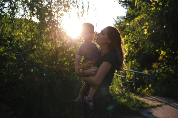 Front View mor och baby son kramas på vägen på sjön på sommaren kvällstid — Stockfoto