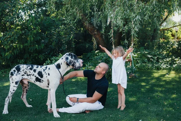 Vacker liten blond Baby flicka har glad kul leende ansikte spelar i en vit klänning med sin pappa och en hund, barn porträtt. Barn familj — Stockfoto