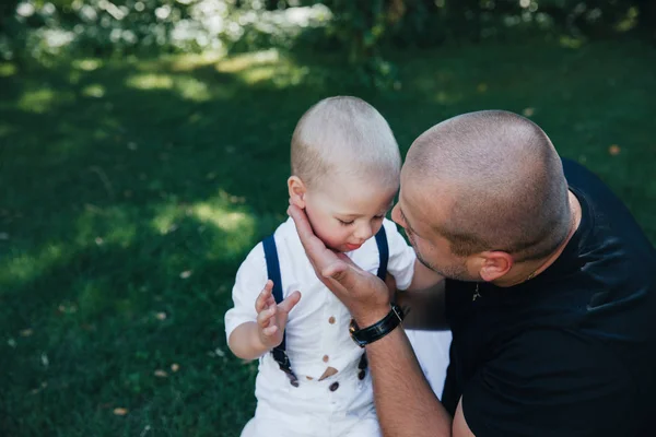 Zweijähriges Kind im Park, in weißen Shorts und weißem T-Shirt mit Papa. blonder Junge mit blauen Augen. fröhliches Kind im Sommerpark. Lachendes Baby in der Natur. — Stockfoto