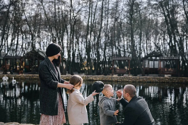Feliz bela família de mãos dadas e caminhando à beira do lago no dia de outono . — Fotografia de Stock