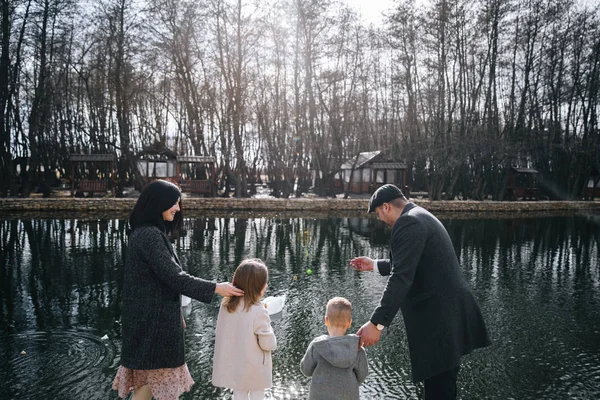 Happy beautiful family holding hands and walking by seashore on autumn day. — Stock Photo, Image