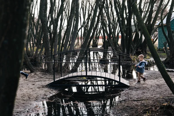 Los niños se divierten y corren a través del puente. Los niños juegan cerca del agua. niños felices corriendo cerca del lago —  Fotos de Stock