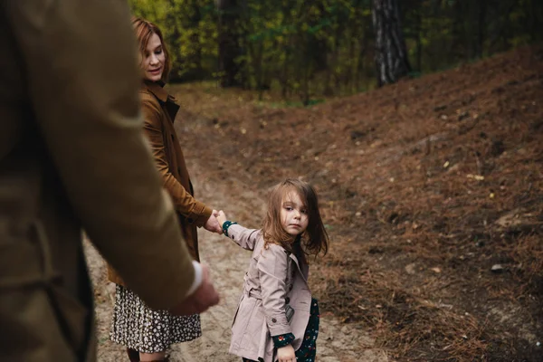 Young father, mother and little toddler daughter girl in a coat walking in the autumn forest. — Stock Photo, Image