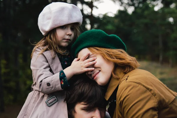Ung far, mor och lilla småbarn dotter flicka i en basker och en kappa promenad hålla händerna i höst skogen. — Stockfoto