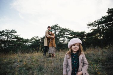 Sonbahar ormanında bir ceket yürümek Genç Baba, anne ve küçük yürümeye başlayan kız kızı.