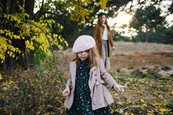 Genç Anne ve küçük Toddler kızı kız sonbahar ormanda yürüyor.