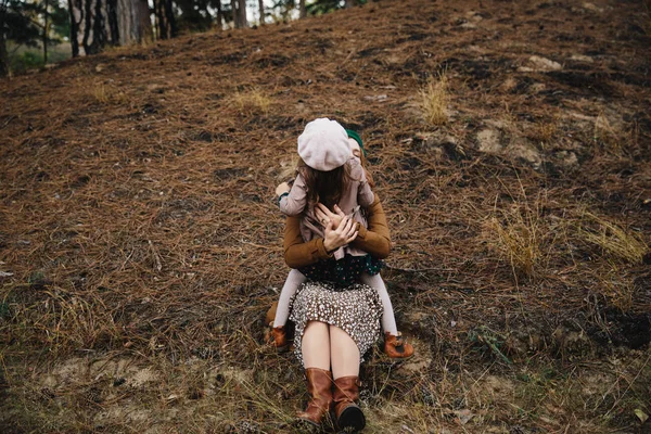 แม่น้อยกับลูกสาวน้อย มีความสนุกสนานกันในป่าฤดูใบไม้ร่วงบนพื้นดิน . — ภาพถ่ายสต็อก