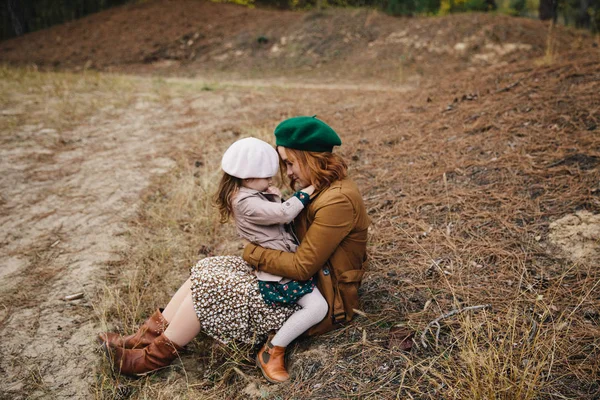 Junge Mutter und kleine Kleinkind Tochter Mädchen haben Spaß miteinander im herbstlichen Wald auf dem Boden. — Stockfoto