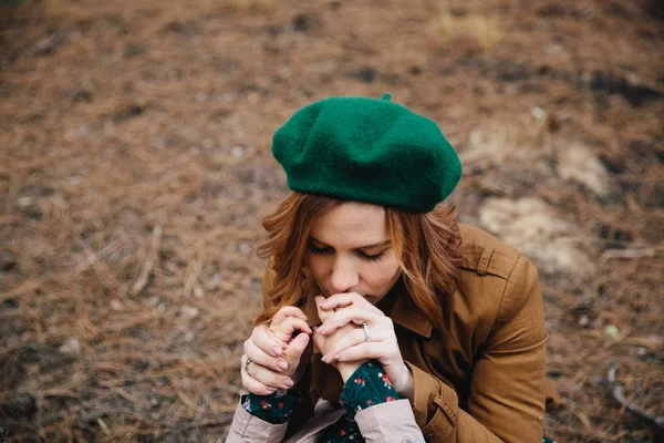 Young mother in a beret kissing daughters hands in the autumn forest. — Stock Photo, Image