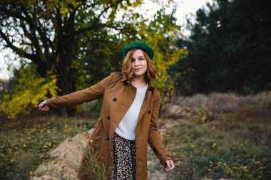 bej bir ceket ve Kuru Çim ve sonbahar ağaçları arka planda bir Bert içinde adil saçlı kız.