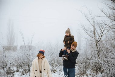 Mutlu bir aile kar yolunda yürür. Anne, baba, kızı arka plan kış açık havada durmak.