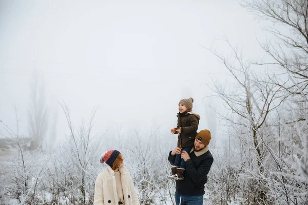 Happy family having fun on the snow field background. Dad puts her daughter up.