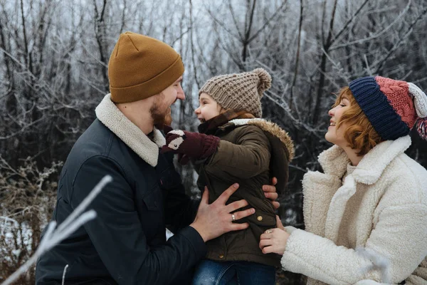 Lycklig familj i kappor och hattar ha kul på snön fältet bakgrund. — Stockfoto