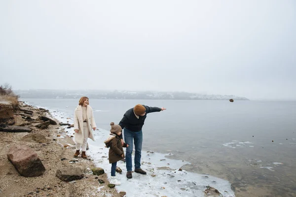 Família em casacos andando nas margens de um rio congelado — Fotografia de Stock