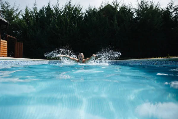 Bahçedeki yüzme havuzuna atlayan genç adam. sağlıklı yaşam tarzı. Yan görünüm — Stok fotoğraf