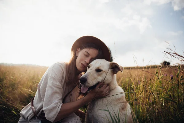 Bella giovane donna rilassata e spensierata godendo di un tramonto estivo con il suo bel cane — Foto Stock