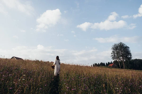 Menina na moda em vestido de outono elegante com belo chapéu andando no campo com flores e palha . — Fotografia de Stock
