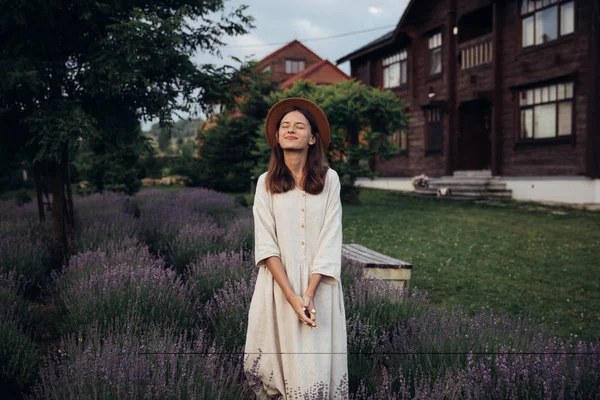 Weiß gekleidete dunkelhaarige Frau genießt auf Lavendelfeld auf dem Landhaushintergrund — Stockfoto