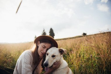 Güzel genç kadın rahat ve kaygısız onu güzel köpek ile bir yaz günbatımı zevk
