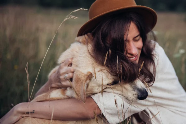 Bela jovem mulher relaxada e despreocupada desfrutando de um pôr do sol de verão com seu lindo cão — Fotografia de Stock