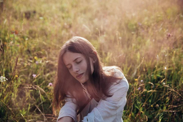 Frau genießt Natur und Sonnenlicht auf Wiese und Blumen. Feld bei Sonnenaufgang. — Stockfoto
