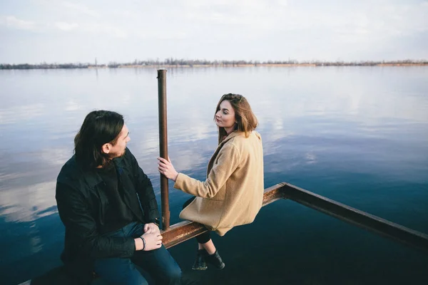 Young romantic couple in coats enjoying autumn landscape on the river background — Stock Photo, Image