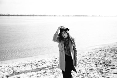 Sıcak paltolu genç çift nehir kıyısında eğleniyor. Siyah beyaz fotoğraf