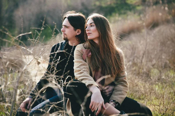 Sonriente pareja sentado en el campo mamparo contra el paisaje —  Fotos de Stock