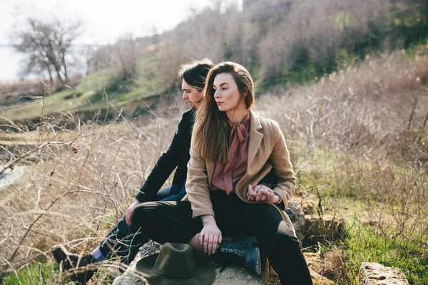 Sonriente pareja sentado en el campo mamparo contra el paisaje —  Fotos de Stock