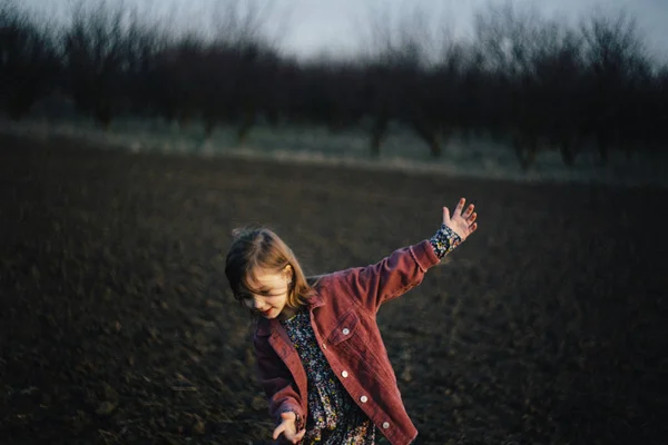 Girl in autumn coat walking through wheat field on sunset. — Stock Photo, Image