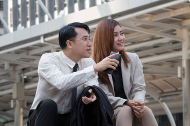 İş adamı ve kadın işlerinden bahsediyorlar ve başarılarını güler yüzle tartışıyorlar. İşadamı hedefi işaret ediyor.